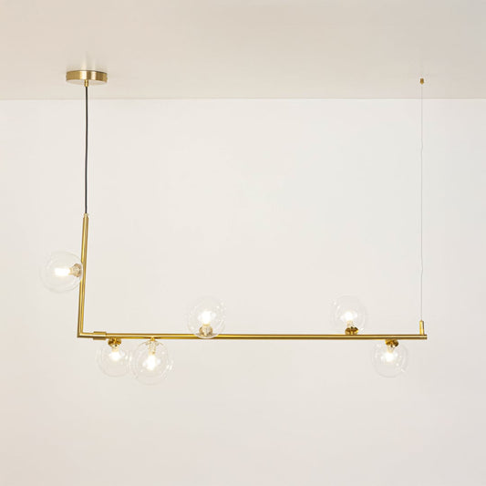 Gold linear chandelier with clear glass globes illuminated on a white background showing its modern design.