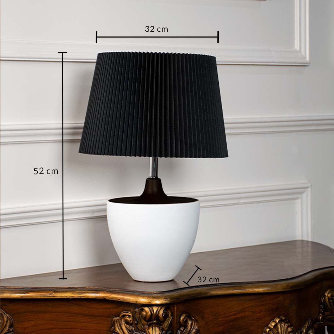 Black table lamp with pleated shade and white ceramic base showing 52 cm height and 32 cm width dimensions.