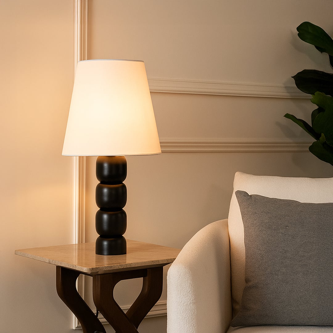 Modern table lamp with white tapered shade and stacked black rounded base adding warm ambient lighting that enhances stylish contemporary interior home decor settings.