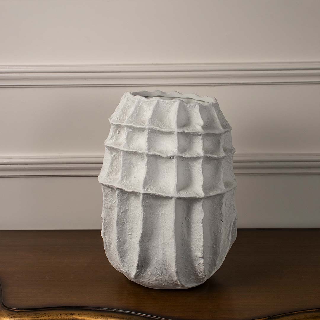 White sculptural ceramic vase displayed on white background with ribbed geometric texture for minimalist modern decor accent.