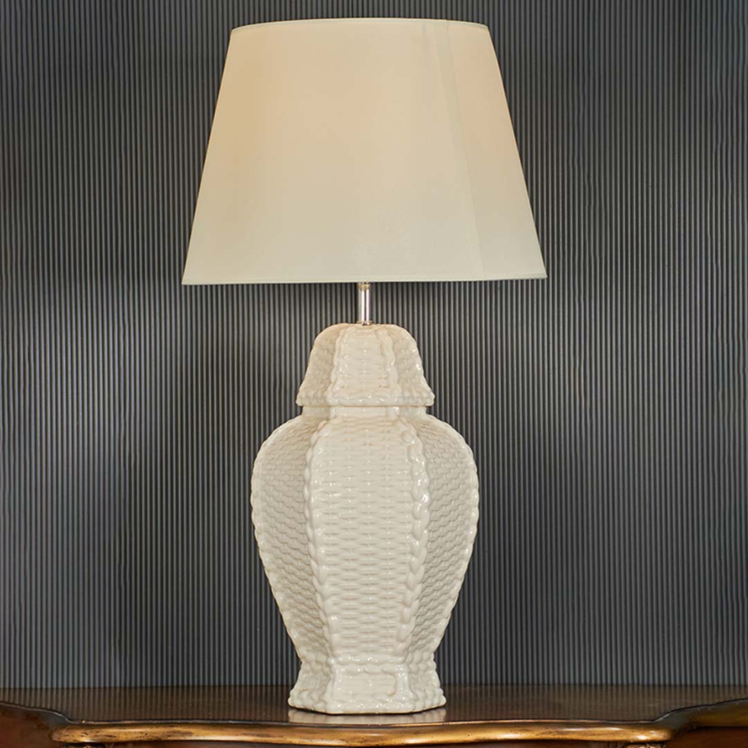 White ceramic textured lamp turned on with cream shade highlighted on a dark background creating a refined modern decor accent for premium interiors.