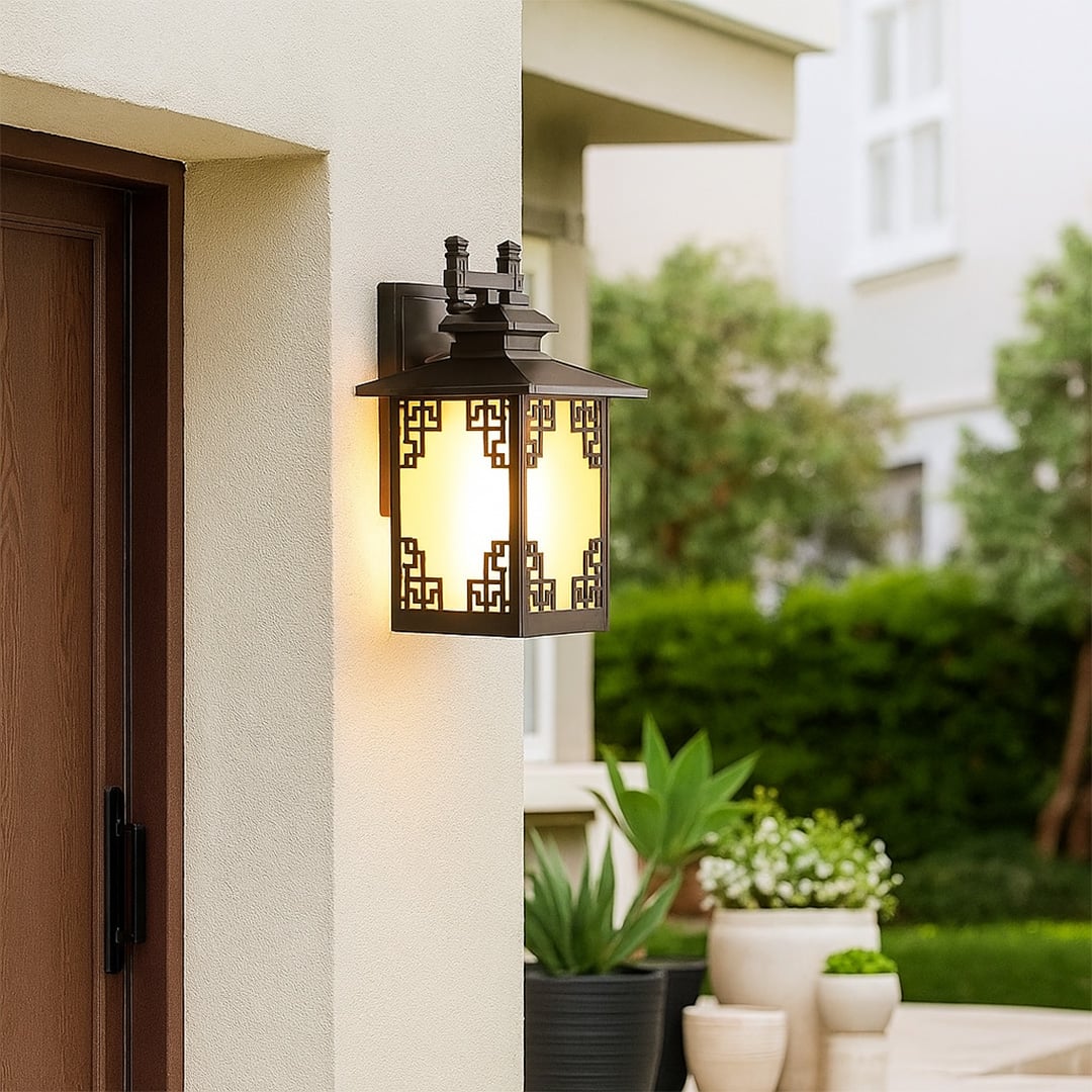 Warm glowing brown metal outdoor lantern mounted beside a door adding inviting ambient lighting with frosted glass and decorative detailing to exterior walls.