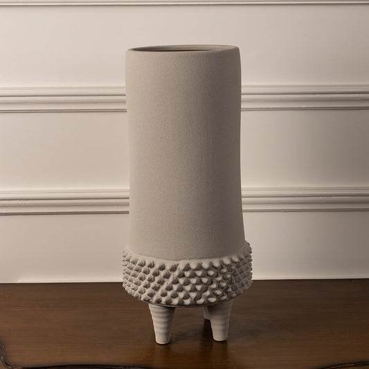 Elegant beige ceramic vase with textured detailing and raised legs shown on plain white background for interior decor.